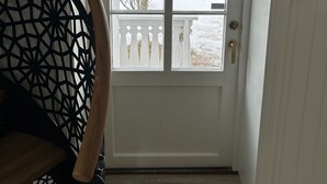 A white door with a glass panel, a metal handle, and a red emergency outlet. - Finsnes Gaard (Senja)