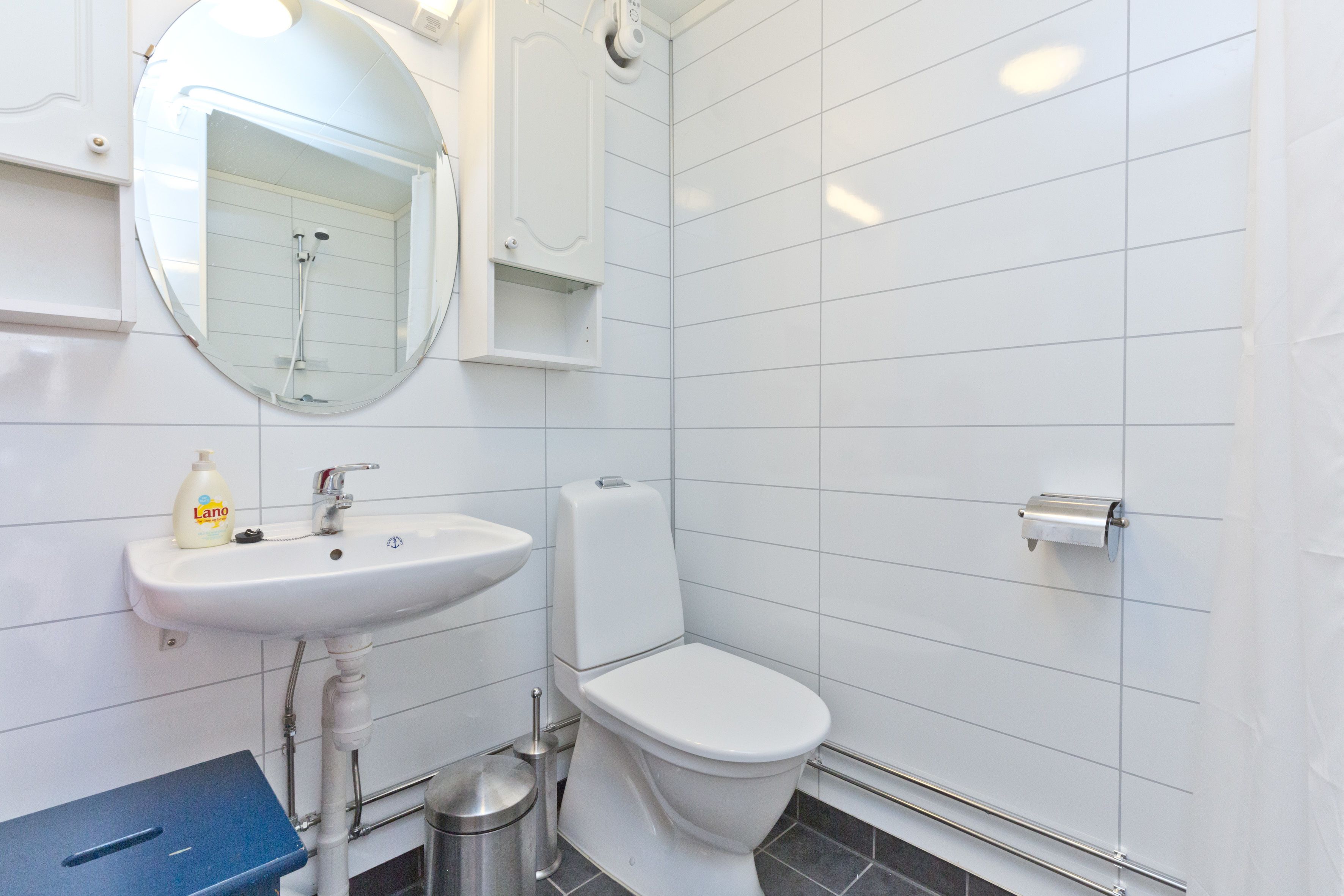 Une salle de bain moderne avec un lavabo blanc, un miroir et des toilettes.