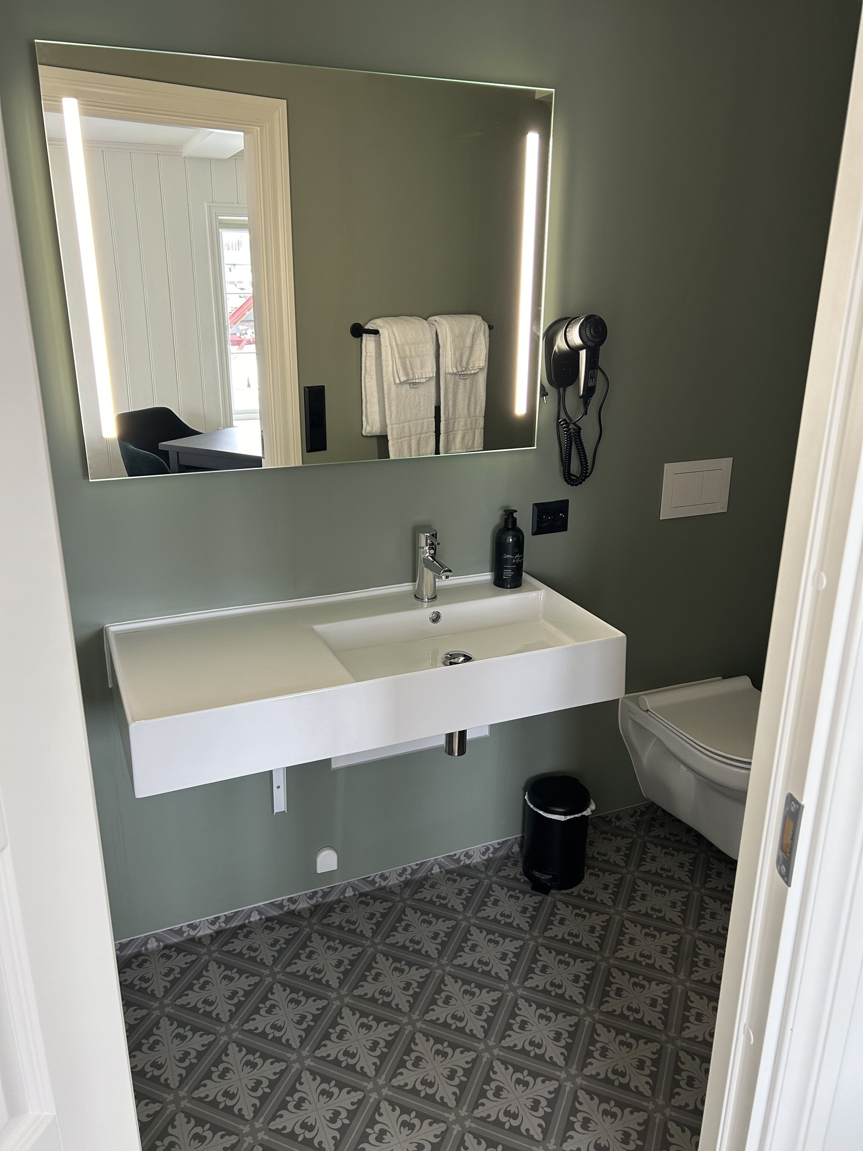 A bathroom with a white sink, a mirror, a hairdryer, and a toilet.