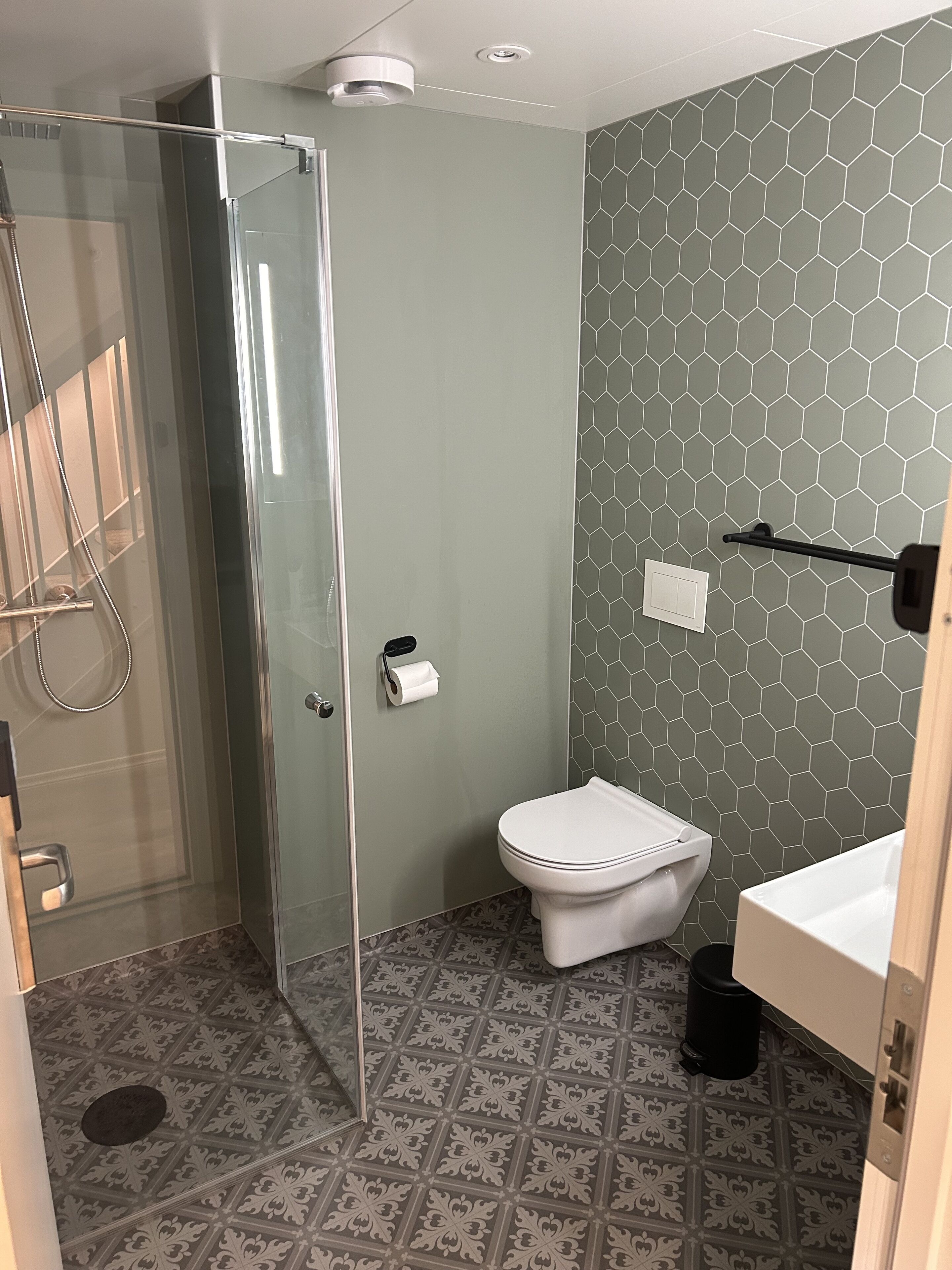 A bathroom with a glass shower enclosure, a toilet, and a sink.