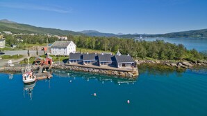 A waterfront property with a large house, dock, and boat. - Finsnes Gaard (Senja)