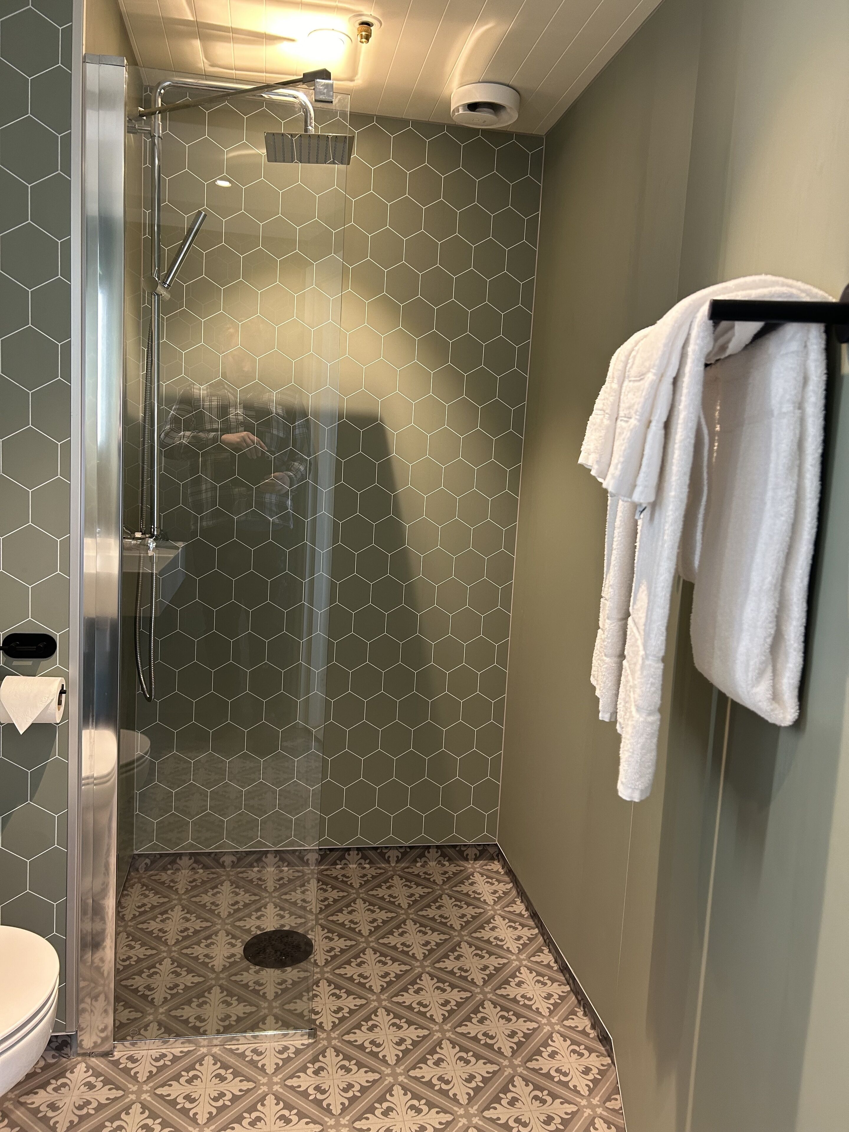 Un baño moderno con ducha de vidrio, inodoro y toallero.