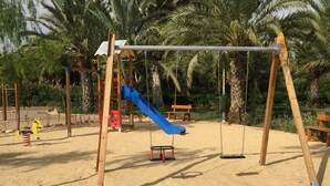 Un parque infantil con columpios, un tobogán y una estructura de madera para escalar.