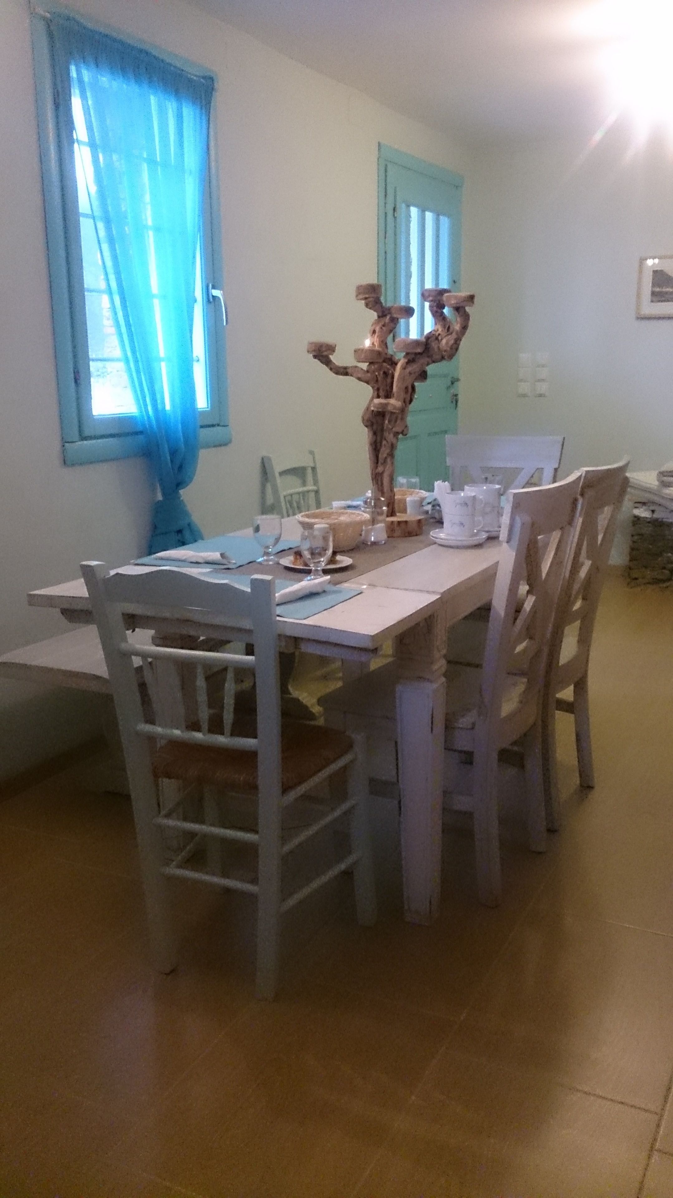 A dining area with a table set for four, surrounded by chairs.