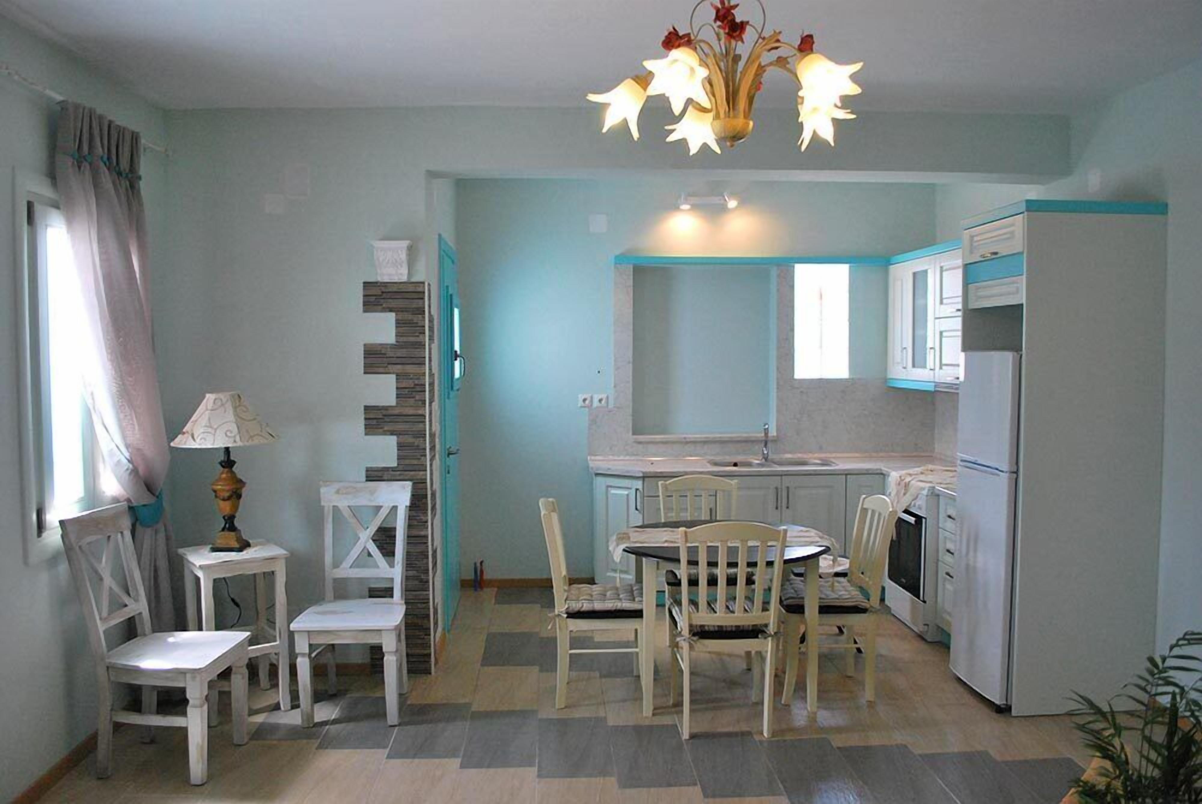 Una cucina compatta con zona pranzo, piano cottura integrato e frigorifero.