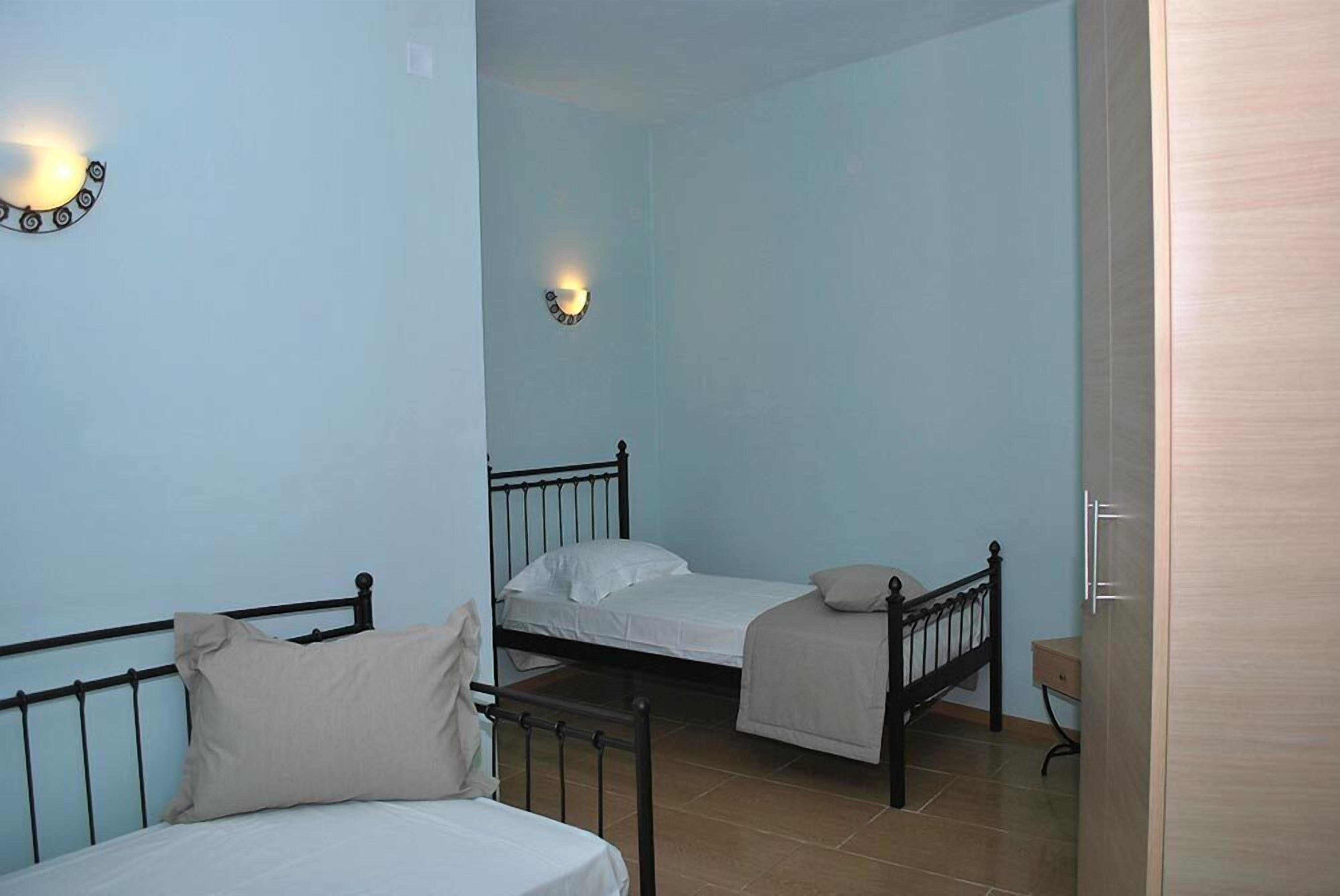 Una habitación con tres camas, un reloj de pared y una mesita de noche.