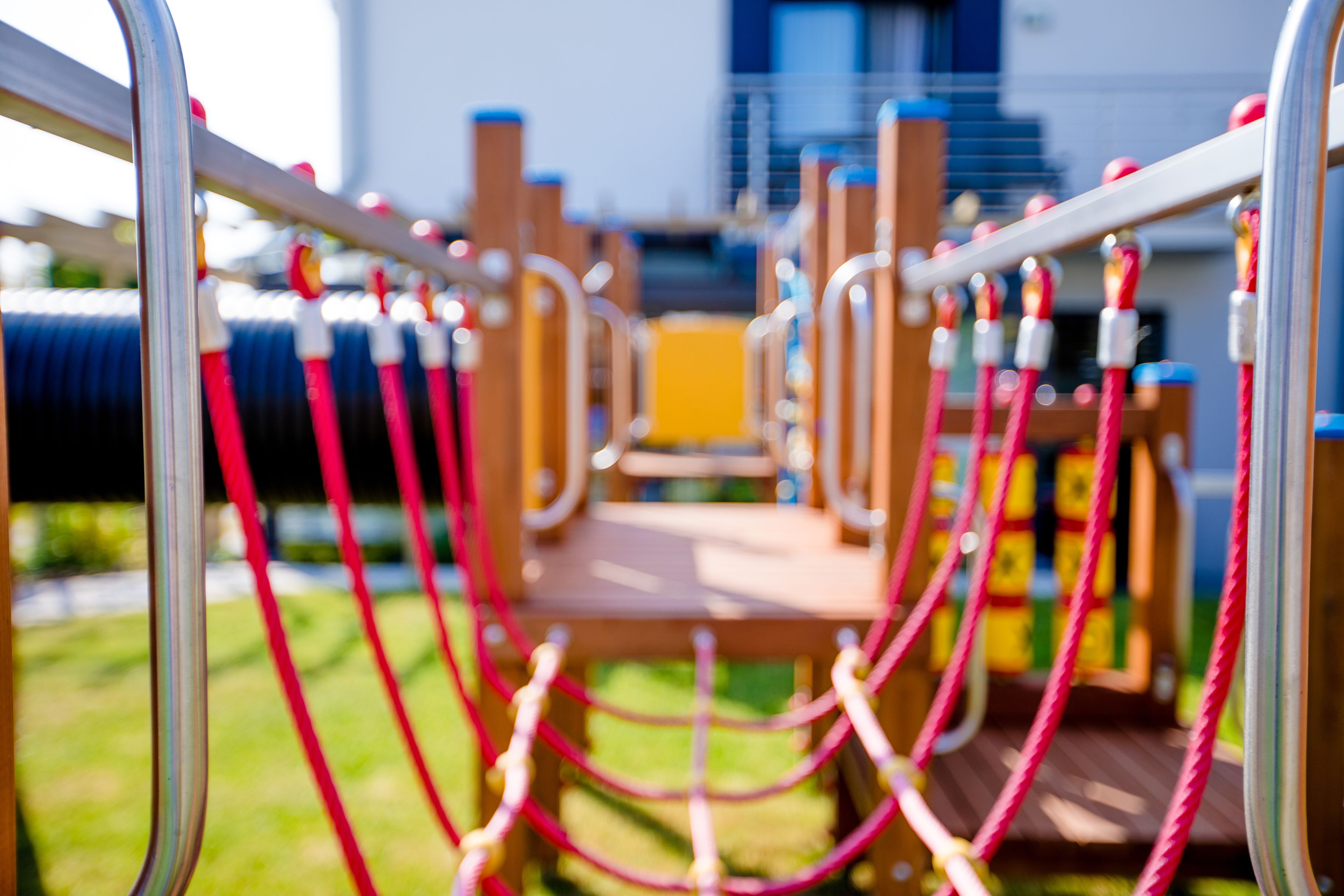 A playground with a metal climbing structure and ropes.