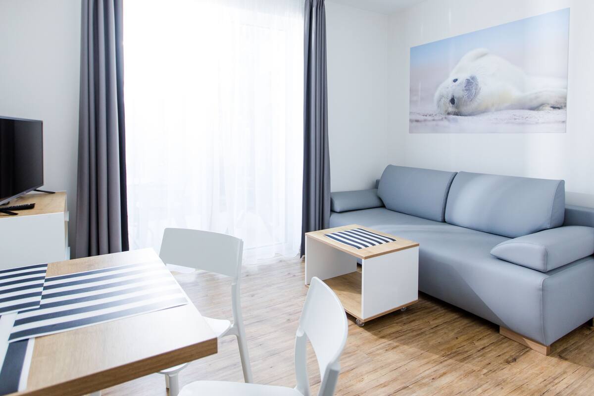 A modern living room with a grey sofa, a wooden coffee table, and a flat-screen TV.