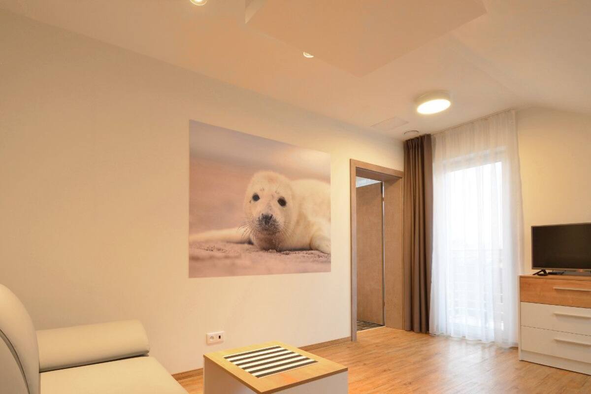 A modern living room with a sofa, a flat-screen TV, a wooden side table, and a wall-mounted picture of a polar bear.