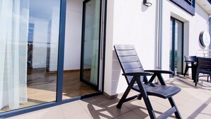 Un espacio moderno para sentarse al aire libre, con un ventanal que da a una habitación, una mesa y sillas.