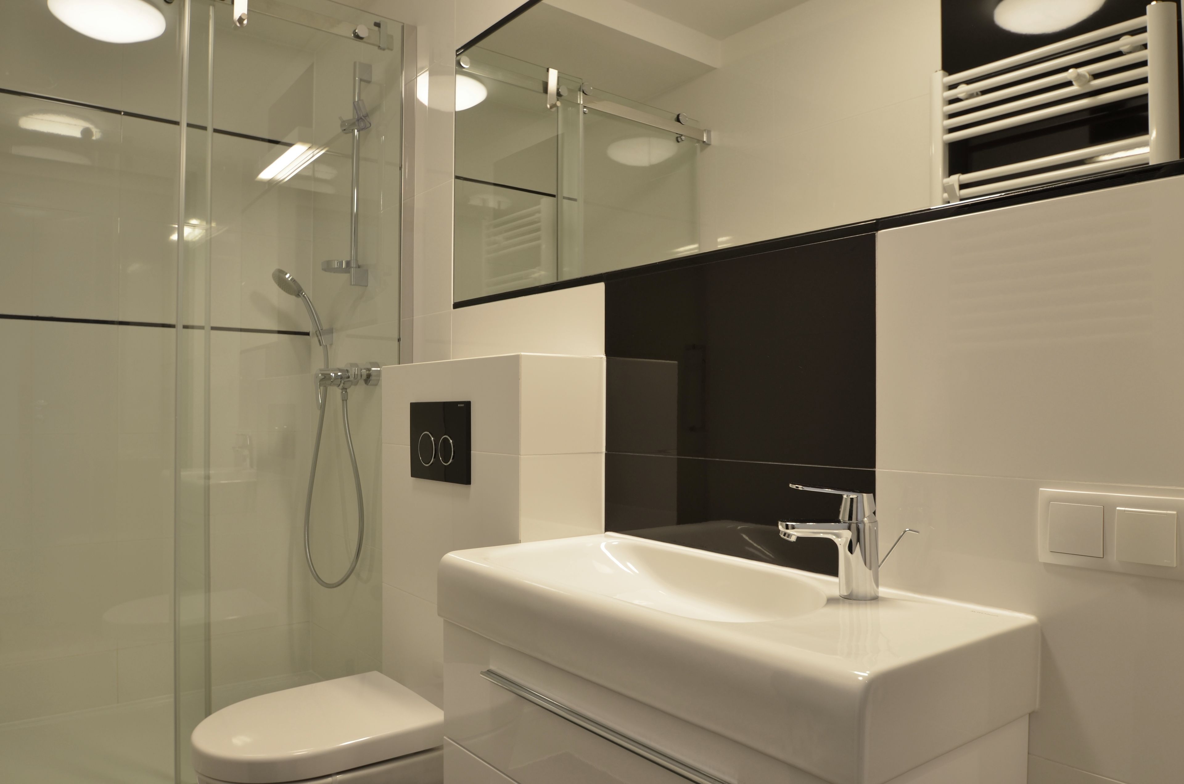 Een moderne badkamer met een douchecabine van glas, een wit wastafelmeubel en een grote spiegel erboven.