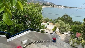 A staircase leading to a beach with a view of the sea and mountains in the background.