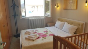 A bedroom with a bed, a nightstand, a radiator, and a window with a view of buildings.