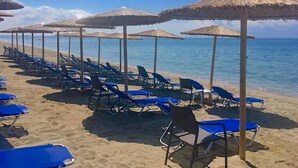 A beach with rows of blue lounge chairs and thatched umbrellas.