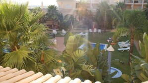 A resort courtyard with lounge chairs, palm trees, a pool, and a building with balconies. - Vilamoura dream vacation with fantastic beaches, golf courses and marina (Quarteira)