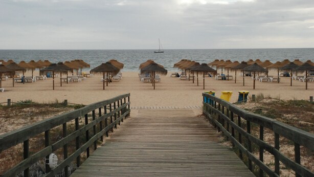 A wooden boardwalk leading to a beach with thatched umbrellas and beach chairs. - Vilamoura dream vacation with fantastic beaches, golf courses and marina (Quarteira)