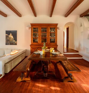 A dining room with a large wooden table, a cabinet with glass doors, and a painting on the wall. - Aquaria Villa (Santorini)