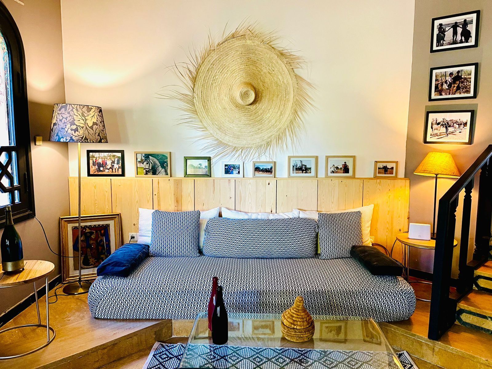 Ein gemütliches Wohnzimmer mit einem gemusterten Sofa, einem großen Wandbehang und einer Treppe.