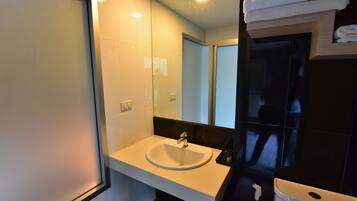Un baño moderno con lavamanos blanco, un espejo y un perchero para toallas.