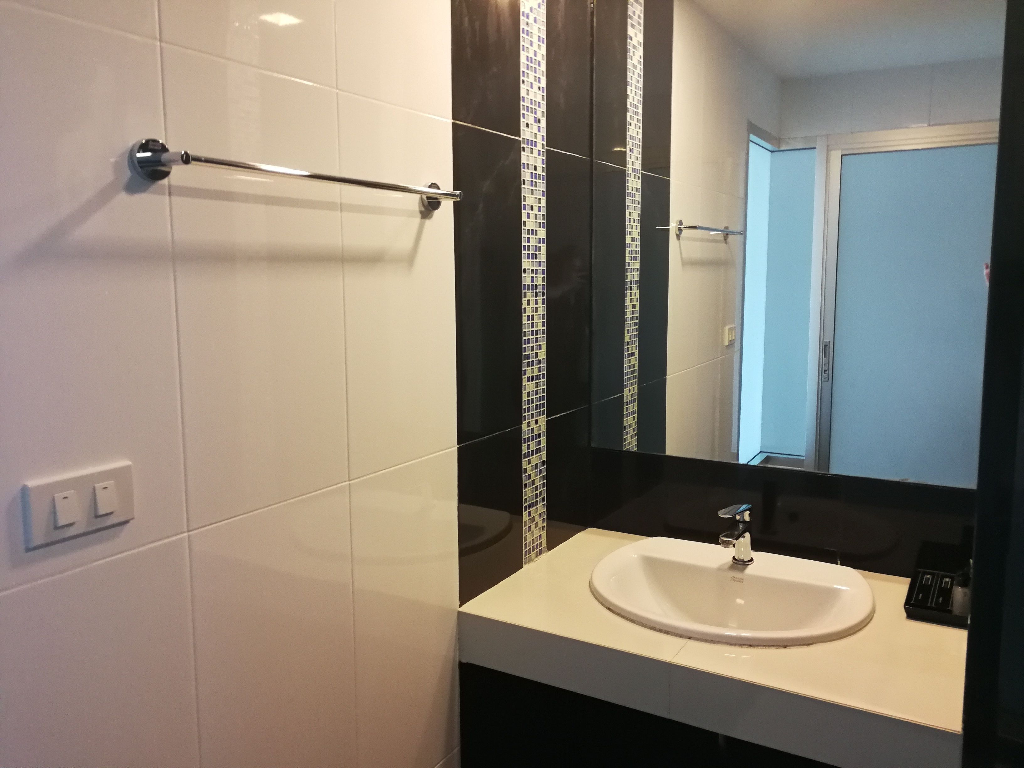 A modern bathroom with a white sink, a mirror, and a towel rack.