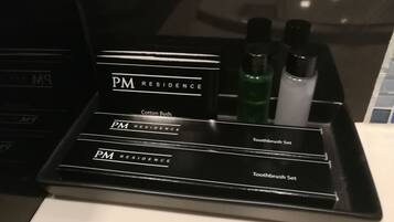 A black tray with PM Residence branding, containing a cotton buds set and a toothbrush set.