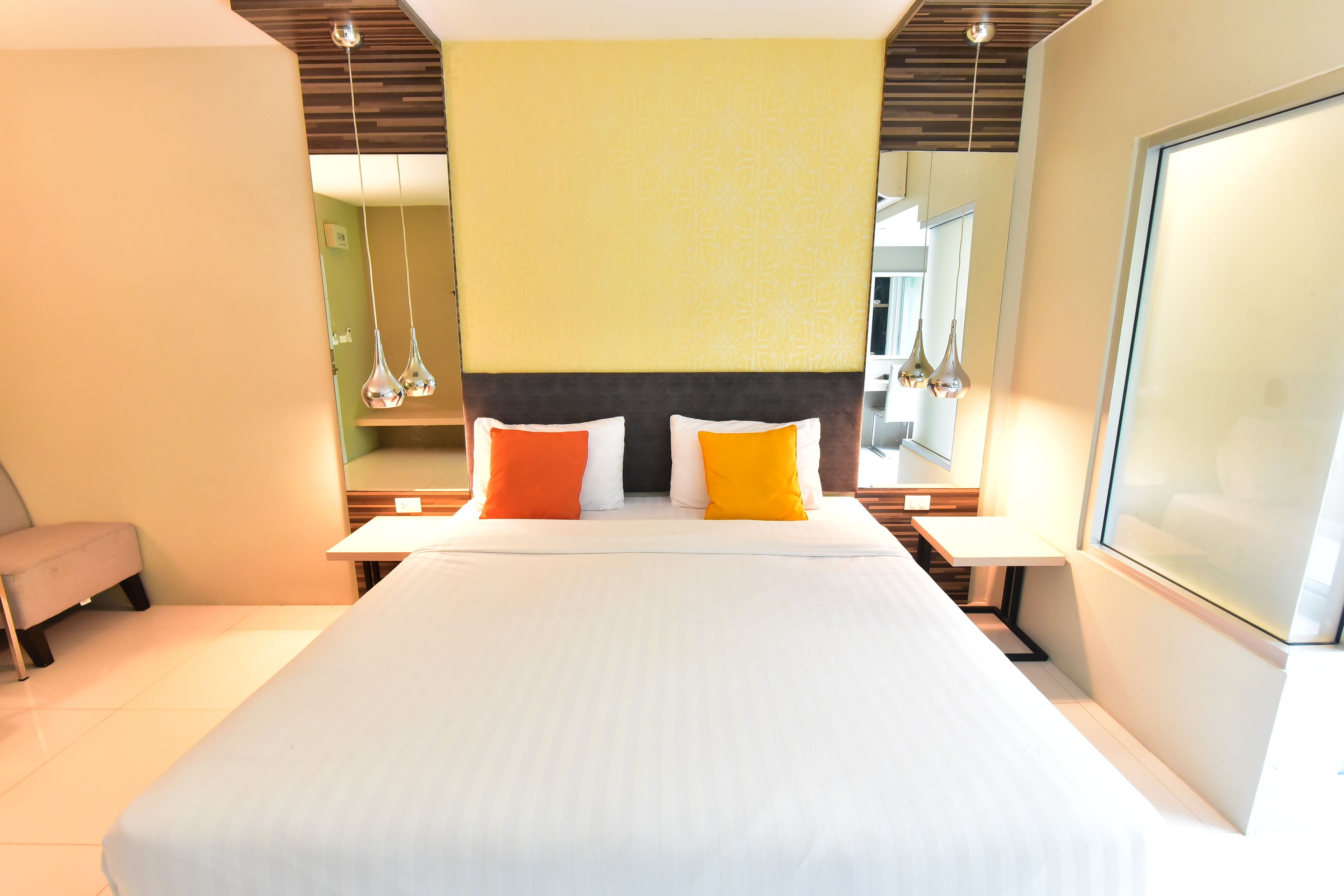 A hotel room with a large bed, two bedside tables, a chair, and a large mirror.