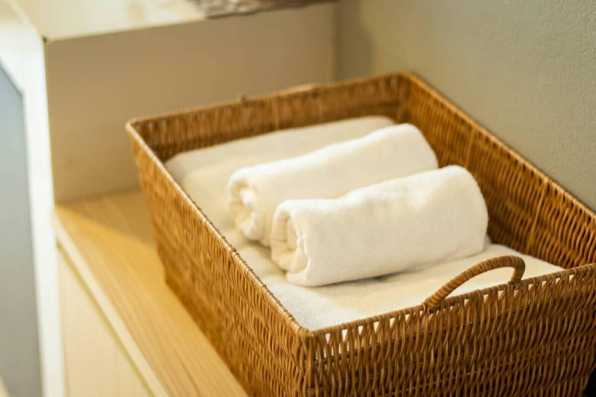 A wicker basket with two neatly folded white towels on a wooden surface.