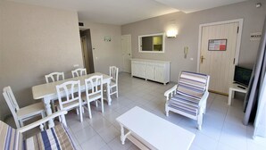 Una sala de estar con comedor, un sofá, un televisor y un aparador.