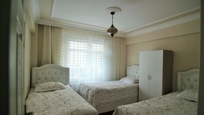 A bedroom with two single beds, a wardrobe, and a window with curtains. - Yılmaz Apart (Istanbul)
