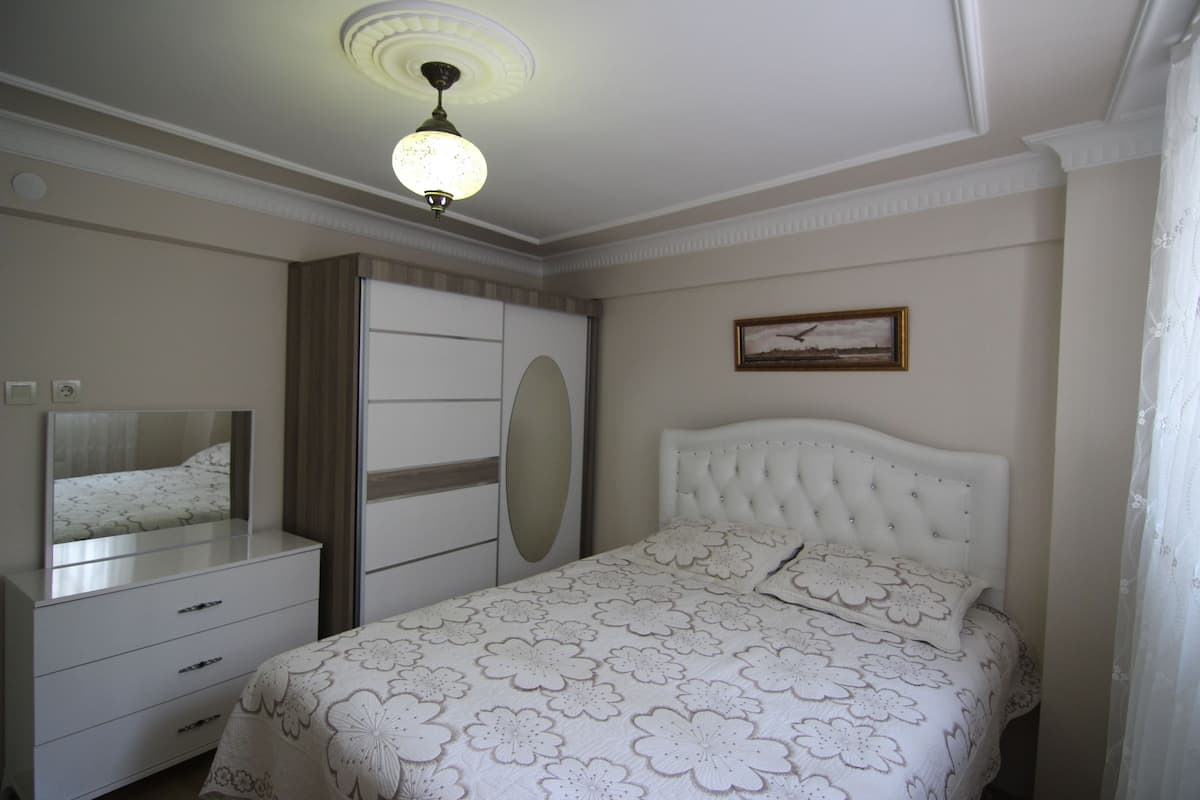 A bedroom with a bed, a dresser, a mirror, and a ceiling light.
