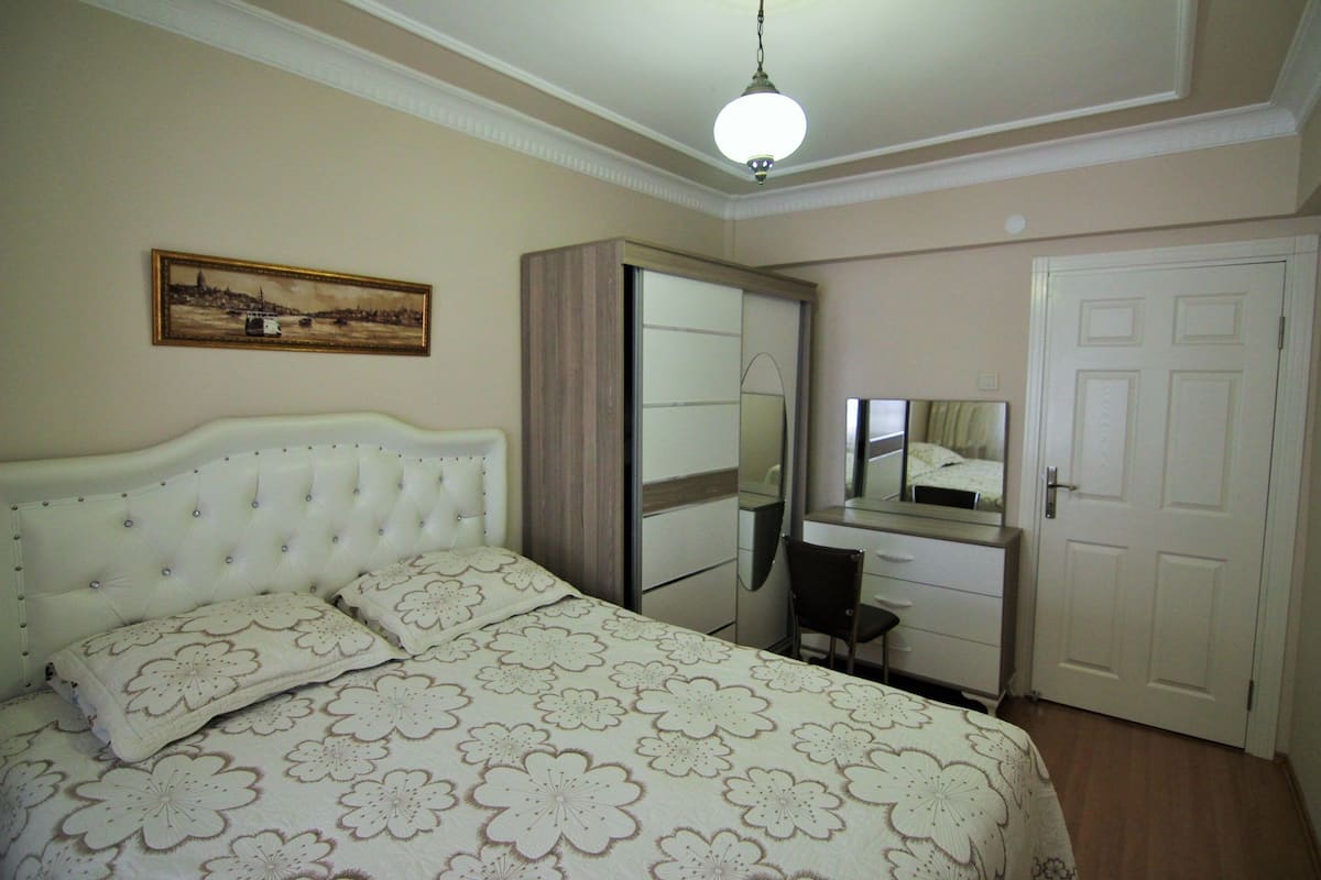 A bedroom with a bed, a dresser, a mirror, and a door.