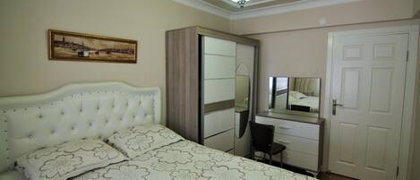 A bedroom with a bed, a dresser, a mirror, and a door.