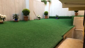 A courtyard with artificial green turf, potted plants, and a tiled pathway. - Yılmaz Apart (Istanbul)