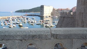 Ein Hafen mit Booten, einer Steinmauer und einem Gebäude mit einem Turm.