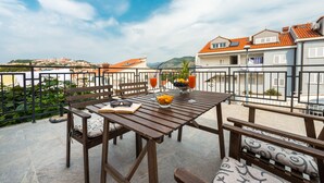 Eine Terrasse mit Holztisch, Stühlen und einer Obstschale.