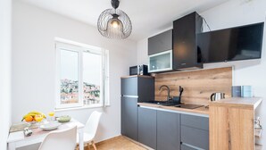 Eine moderne Küche mit grauen Schränken, einer Holzauskładung, einer eingebauten Mikrowelle und einem großen Fenster mit Blick auf die Stadt.