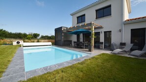 A modern house with a swimming pool, patio furniture, and a pergola. - Villa 4 by Avecoeur (Saint-Augustin)