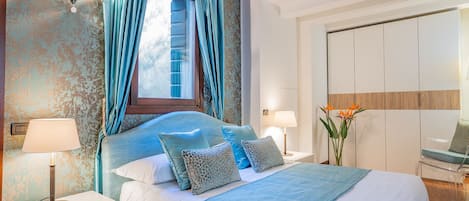 Een slaapkamer met een bed, nachtkastjes, een lamp, een raam met gordijnen en een spiegel.