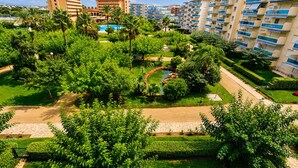 Un hotel con diversi piani, una piscina e vegetazione lussureggiante.