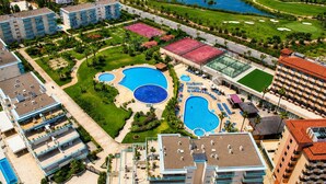 Un hotel con diverse piscine, un campo da tennis e un percorso per golf.