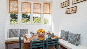 A dining area with a wooden table, blue chairs, a bench with patterned cushions, and a basket of fruit. - Nice typical Menorcan house, with good location (es mercadal)