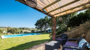 A covered outdoor seating area with wicker furniture, a pool, and a view of the countryside. - Nice typical Menorcan house, with good location (es mercadal)