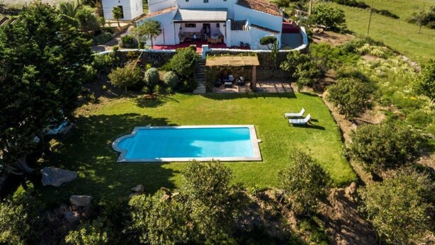 A large house with a swimming pool, surrounded by lush greenery and hills in the background. - Nice typical Menorcan house, with good location (es mercadal)