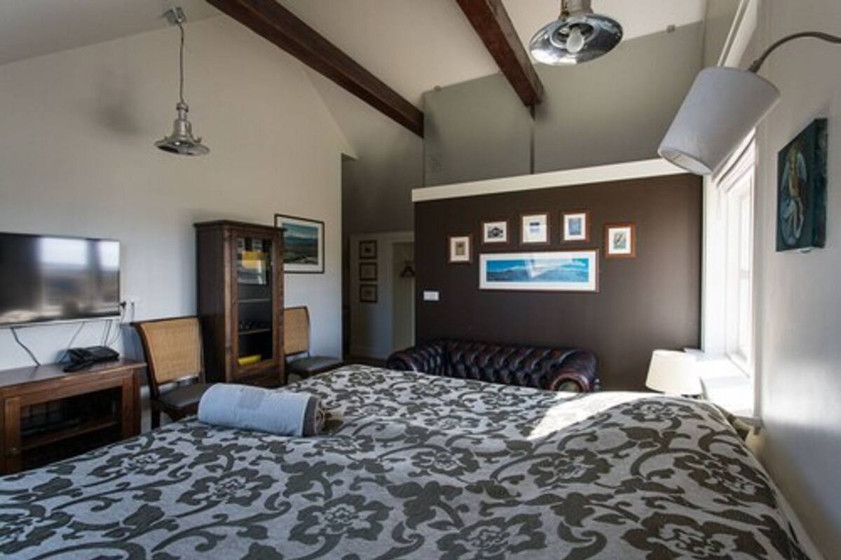 Un dormitorio con una cama grande, televisor, armario y cuadros en la pared.