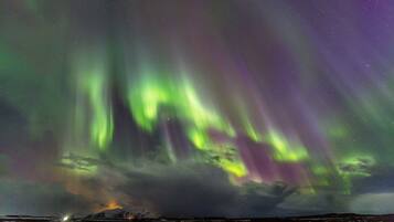 Paesaggio innevato con una montagna sullo sfondo e l'aurora boreale nel cielo.