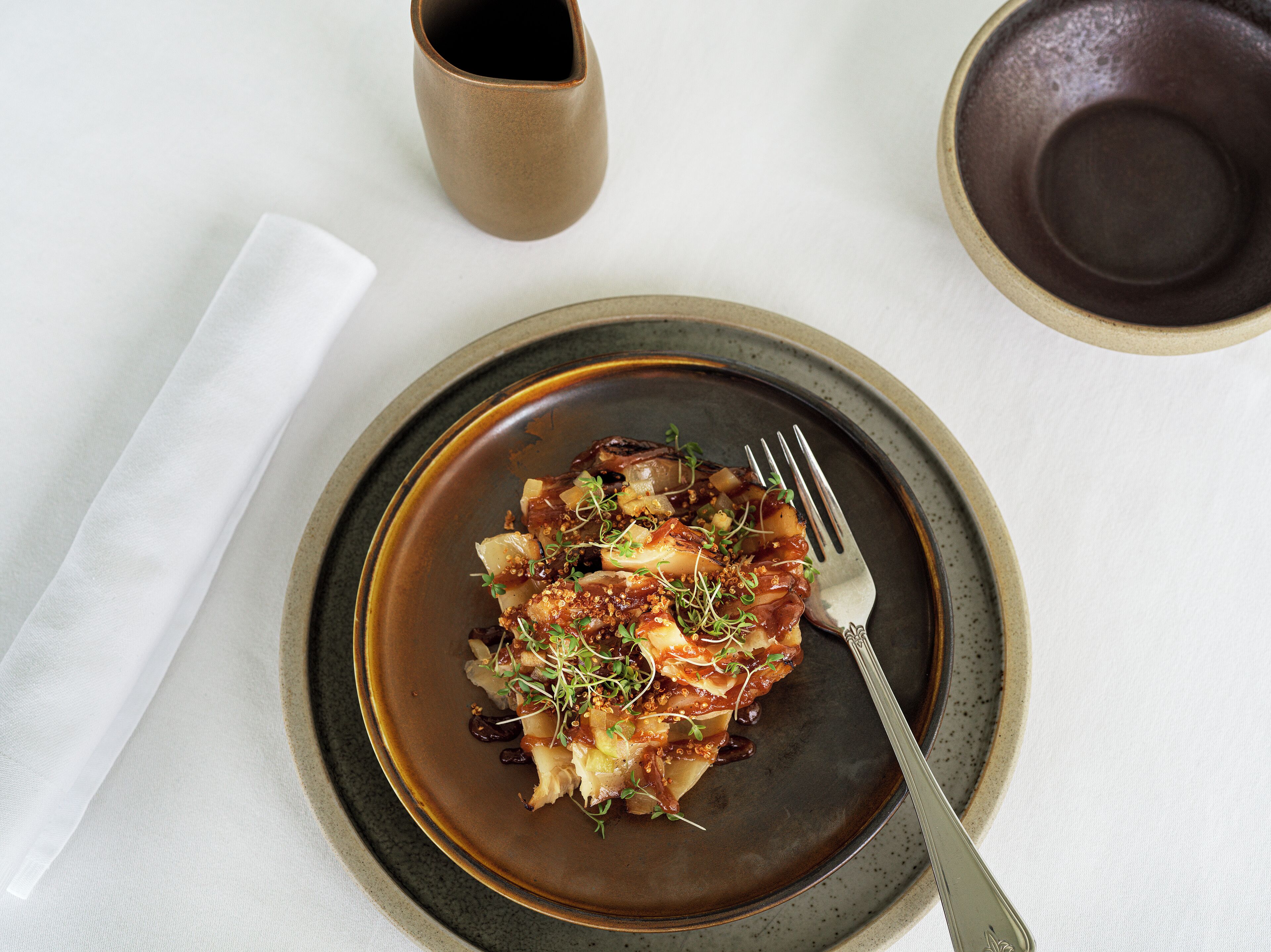 A plate of food on a table with a napkin and a cup.