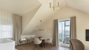 A modern hotel room with a large window, a dining area, and a cozy seating space. - Hótel Búðir (Snæfellsbær)