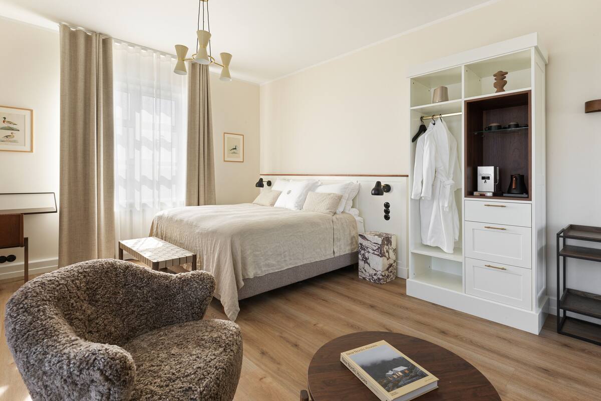 Un dormitorio moderno con una cama grande, una mesita de madera, una silla, un armario y un escritorio.