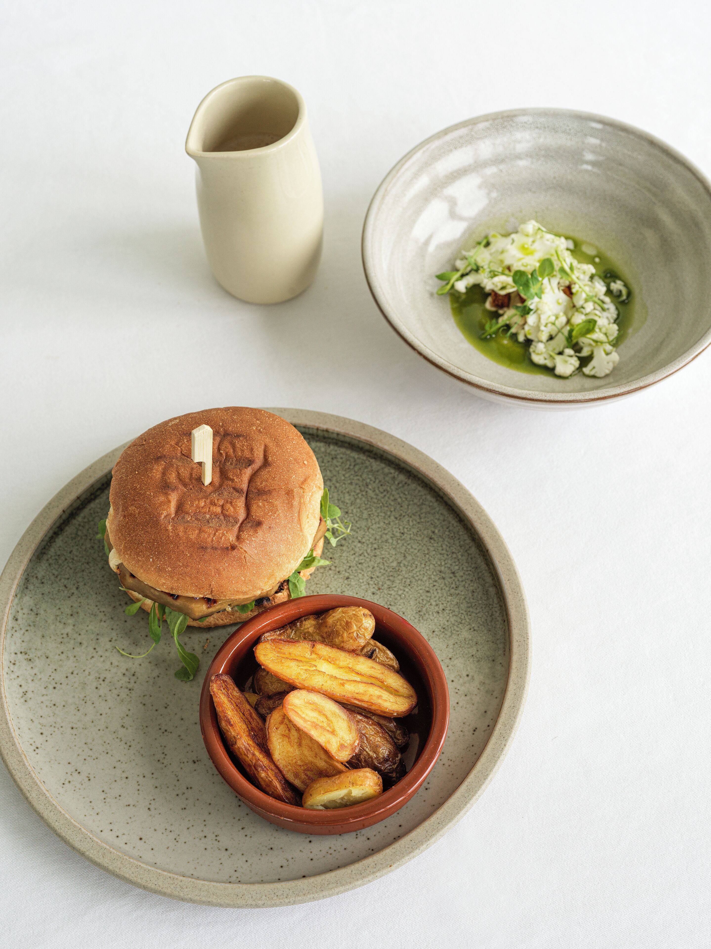 Une assiette avec un sandwich, un bol de frites et un petit saladier de salade.