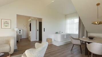 Un salon moderne avec un coin repas, une baignoire blanche et un escalier menant à l’étage supérieur.